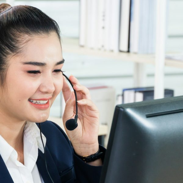 Asian female customer service talking to client with headphone at desk